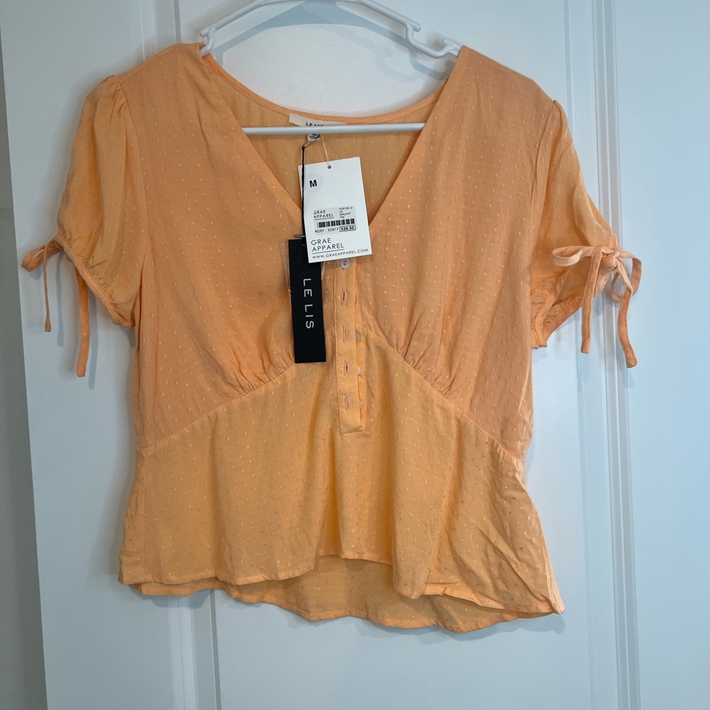 Medium short sleeve peplum top. Soft orange color with polka dot detailing.
